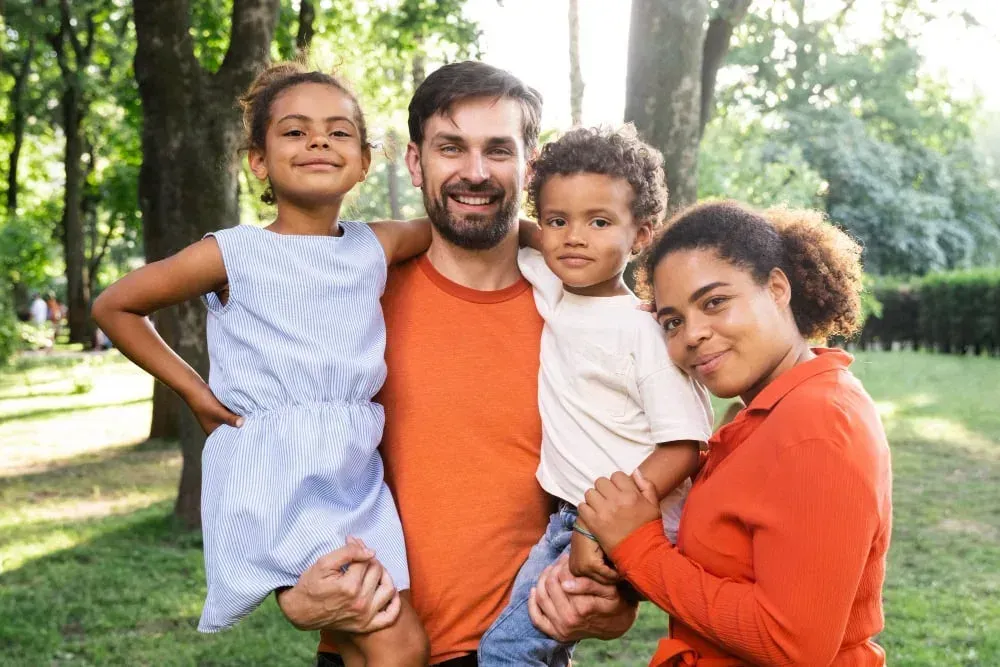 Happy family with a young child smiling outdoors - gentle pediatric dental care at Neola Dental in Minneola, FL
