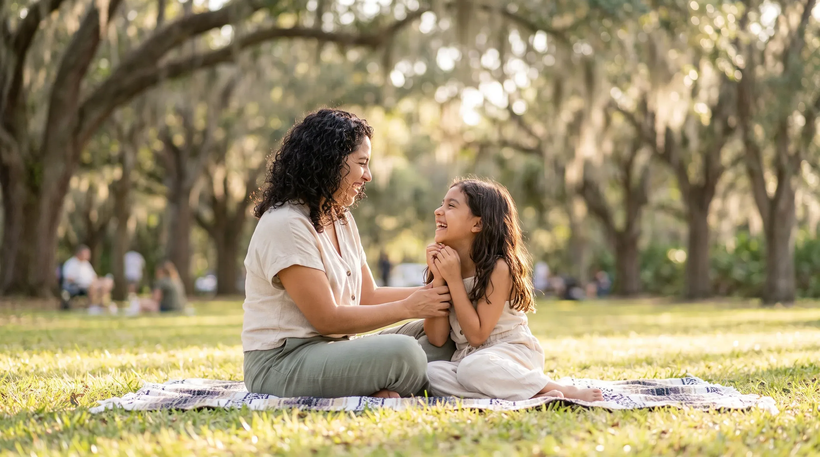 Madre e hija riendo juntas sobre una manta de picnic en un parque cerca de Minneola, FL.