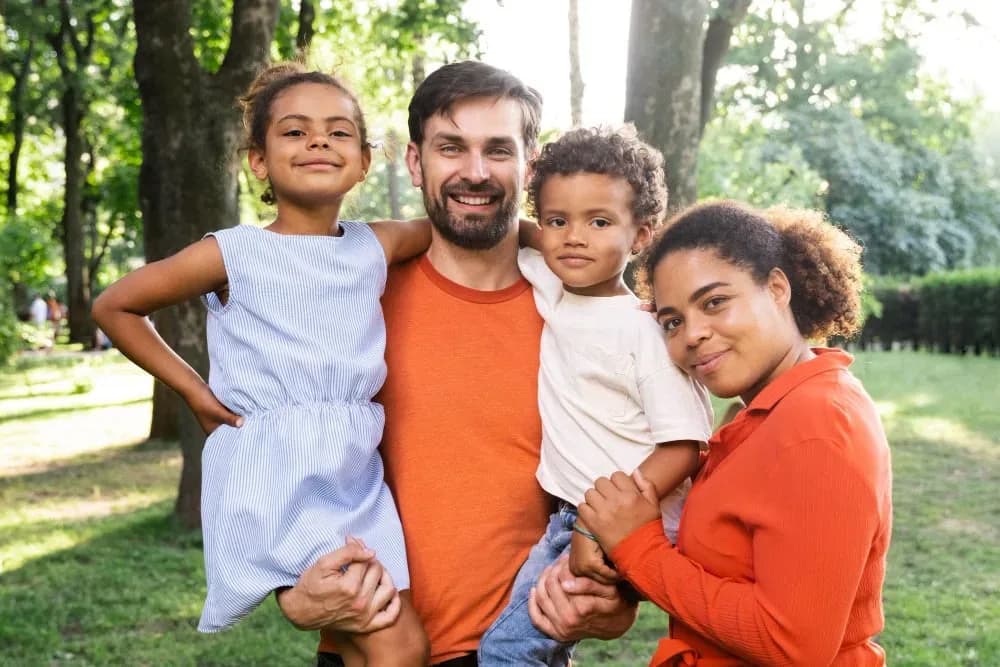 Happy family with a young child smiling outdoors — gentle pediatric dental care at Neola Dental in Minneola, FL