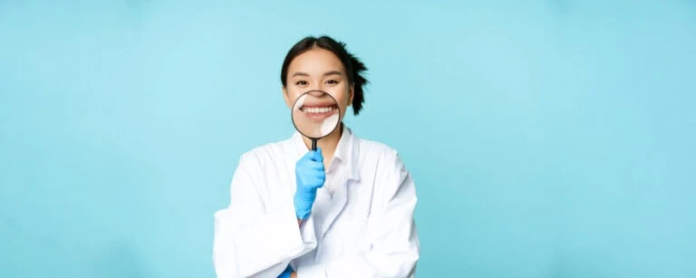 Happy patient smiling at Neola Dental in Minneola, FL, holding a dental mirror, showcasing a healthy, confident smile.