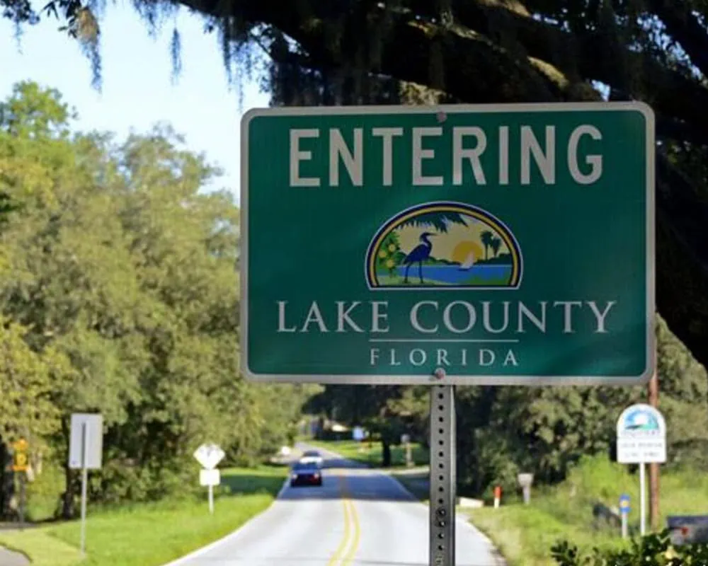 Entrance sign for Lake County, Florida, with scenic logo and green background.
