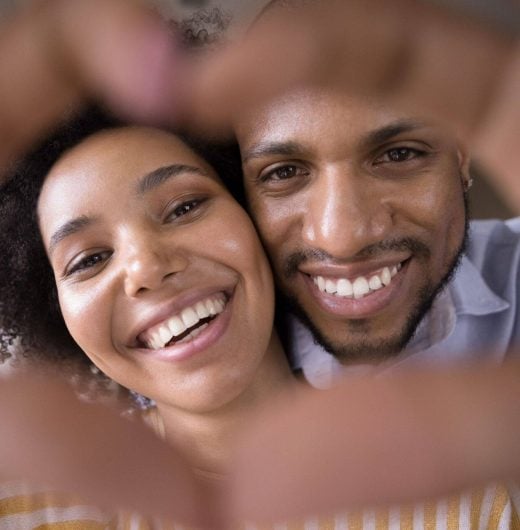 Happy couple embracing and smiling, showing confidence in their dental health after treatment at Neola Dental